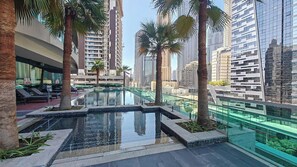 A rooftop pool with palm trees, surrounded by high-rise buildings.