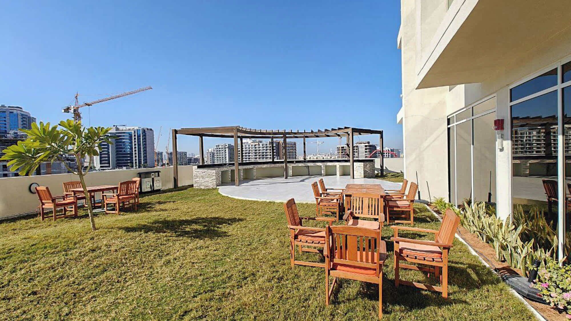 Eine Dachterrasse mit Gartenmöbeln, einer Pergola und Blick auf die Skyline der Stadt.