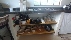 A kitchen with a black countertop, wooden shelves, and various kitchenware. - Refuge in the mountains/near the trail to Pico do Papagaio Garcias Peak and Waterfall (Aiuruoca)