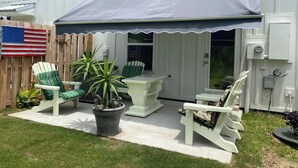 Eine Terrasse mit Gartenmöbeln, einem überdachten Bereich und einem weißen Zaun.