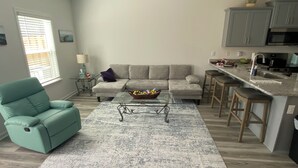 Ein modernes Wohnzimmer mit einem türkisfarbenen Sessel, einem grauen Sofa und einem Couchtisch mit einem Korb.