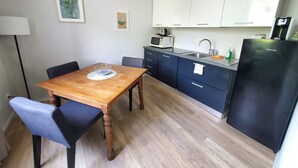 A compact kitchen with a wooden dining table, a microwave, a sink, and a refrigerator. - Nuova Porta dei Musicisti (VERONA)