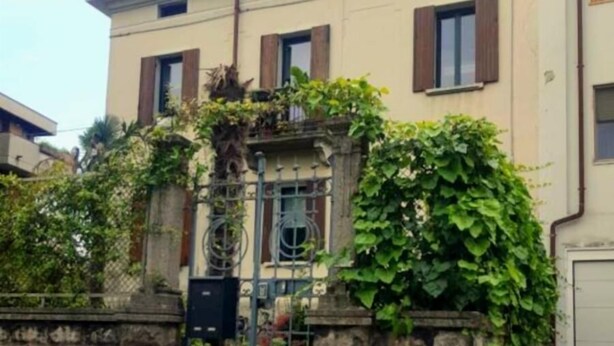 A two-story building with a stone wall and a metal gate. - Nuova Porta dei Musicisti (VERONA)