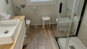 A modern bathroom with a wooden vanity, a toilet, a small round stool, and a glass-enclosed shower area. - Nuova Porta dei Musicisti (VERONA)