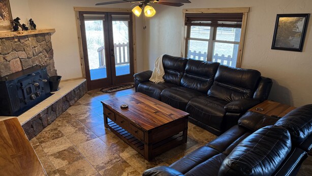 A living room with a stone fireplace, leather sofa, and a wooden coffee table. - Wharton Wilderness Ranch House (South Fork)