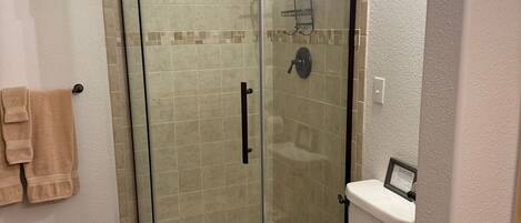 Ein modernes Badezimmer mit Duschkabine, Toilette und Handtuchhalter.