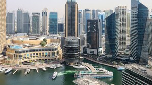 Un hôtel situé au bord de l’eau, doté d’une piscine, d’un port de plaisance et entouré d’immeubles modernes de grande hauteur.