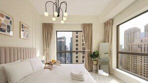 Une chambre d’hôtel avec un grand lit, une table de chevet sur laquelle se trouve un plateau de petit-déjeuner, une plante en pot et une vue sur de hauts immeubles par une grande fenêtre.