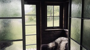 Una habitación acogedora con techo de madera, ventana con vista a la vegetación y un sofá mullido.