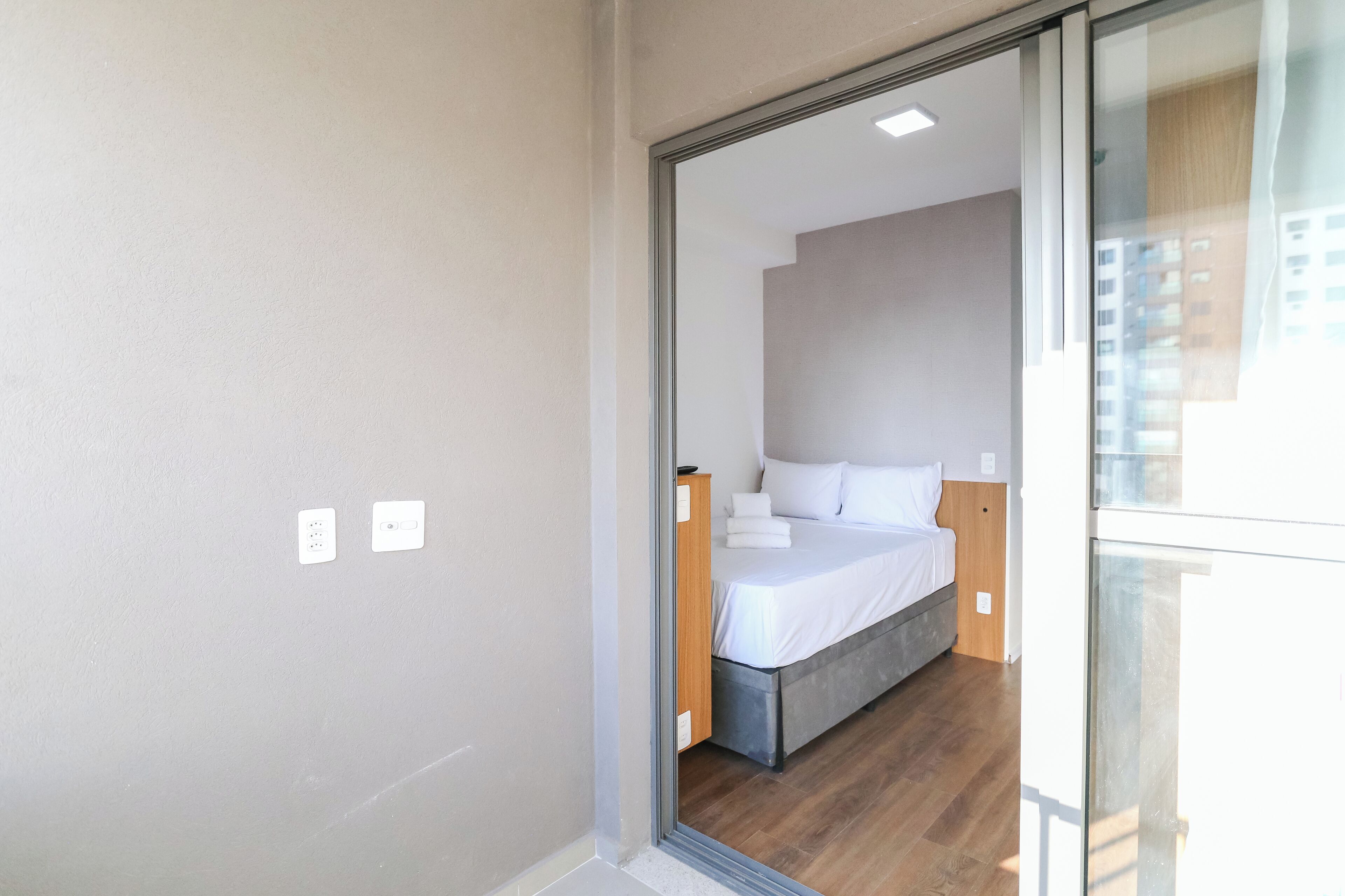 A modern bedroom with a bed, a nightstand, and a wooden headboard.
