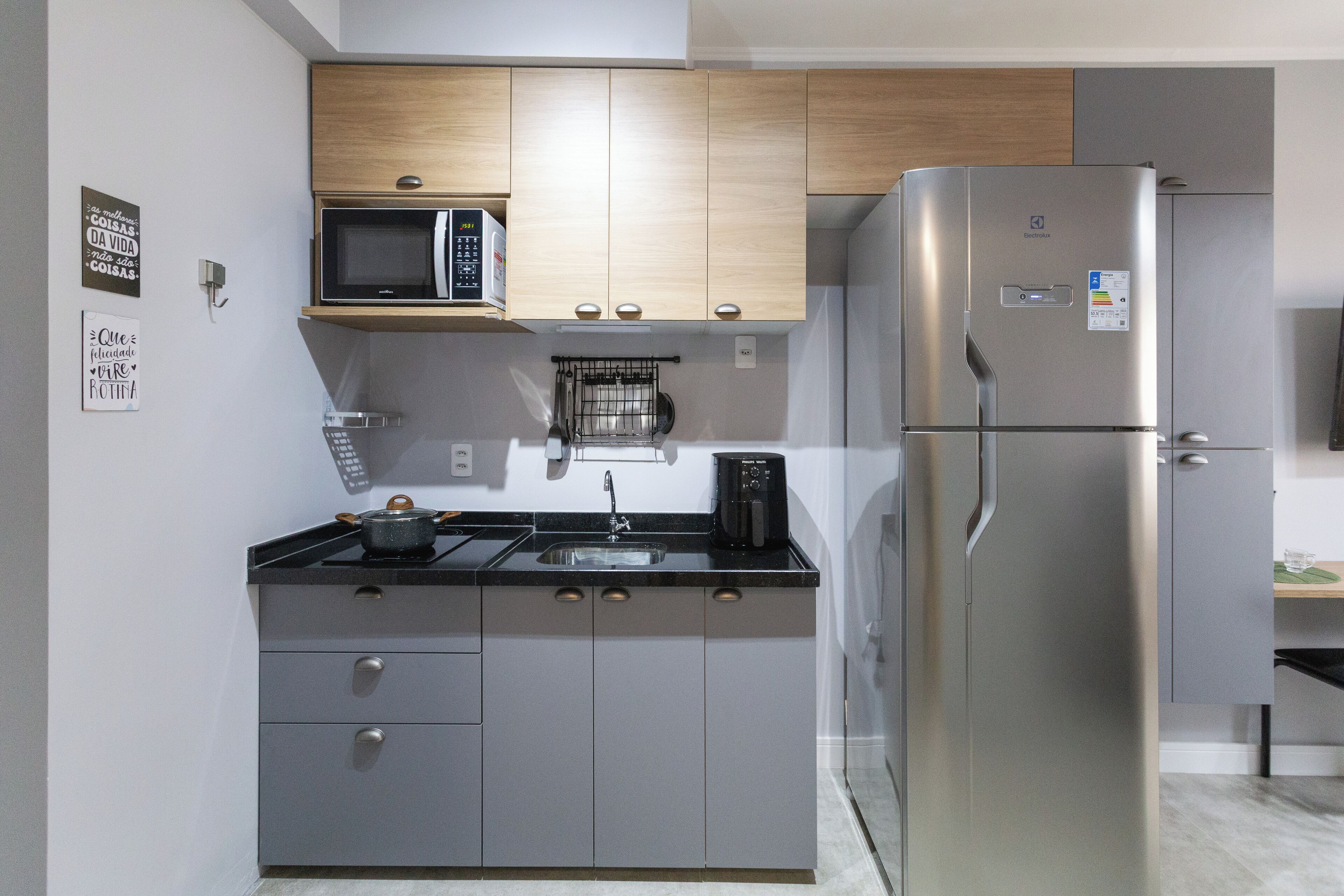 Una cocina moderna con un refrigerador de acero inoxidable, un microondas y una cafetera en la encimera.