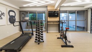 Un gimnasio moderno con cinta de correr, mancuernas y bicicleta estática.