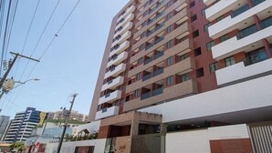 Ein mehrstöckiges Gebäude mit modernem architektonischen Design, das Balkone auf jeder Etage aufweist.
