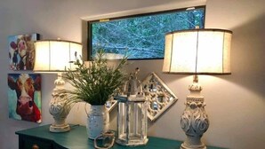 A teal console table with decorative items, including a vase with green plants, a clear glass lantern, and two ornate lamps.