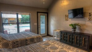 A bedroom with a large bed, a TV mounted on the wall, and a view of the outside.