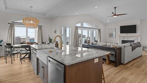 A spacious living area with a kitchen island, dining table, and seating area. - Ocean Views & Surf Fishing Paradise at The Point – Perfect Family Escape! (Emerald Isle)