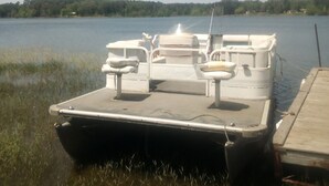 Um barco parado atracado num cais, com relvado à frente e um lago calmo ao fundo.