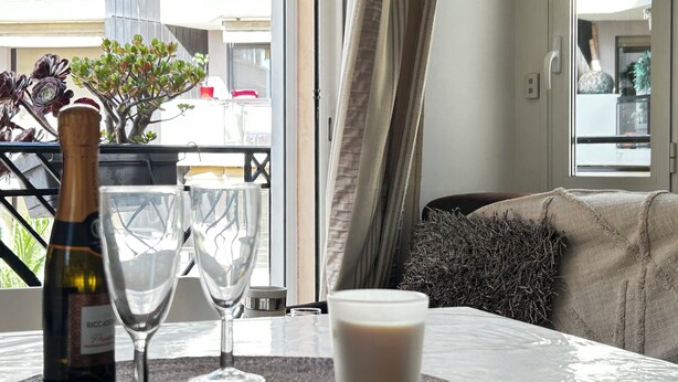A table with a bottle of wine, two wine glasses, and a glass of milk on a textured placemat. - Elegant studio - 50m from the Croisette and the Beach (Cannes)