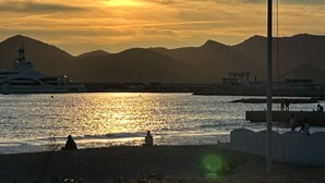 A sunset over a body of water with mountains in the background and a yacht docked nearby. - Elegant studio - 50m from the Croisette and the Beach (Cannes)