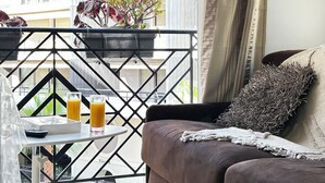 A balcony with a sofa, a small table with a glass of orange juice, and a potted plant. - Elegant studio - 50m from the Croisette and the Beach (Cannes)