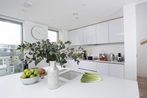 Enjoy a city view from the kitchen window, where a vase with green foliage and a bowl of fresh produce add a touch of natural charm.