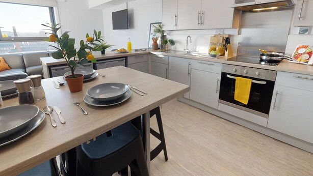 Une cuisine moderne avec des meubles de couleur grise, une table à manger en bois et un four noir.