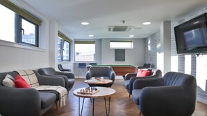 Un espace de détente moderne avec des canapés, une table de billard et un téléviseur à écran plat.