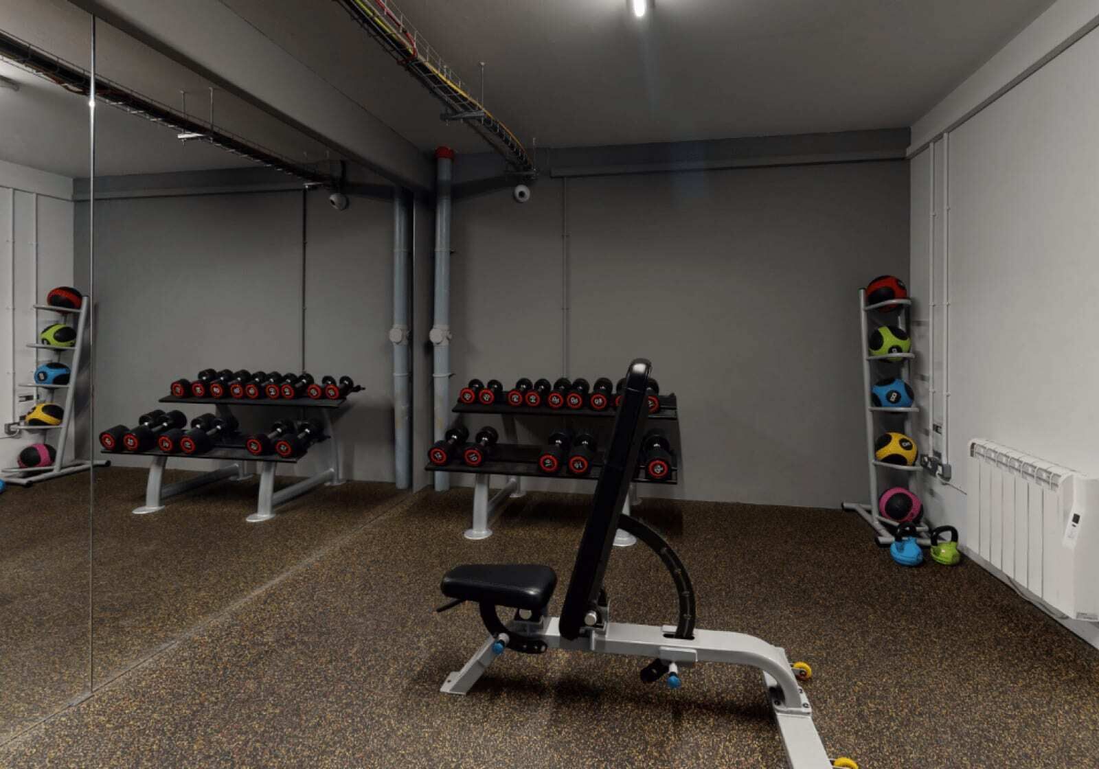 A gym with weightlifting equipment, including dumbbells and a bench.
