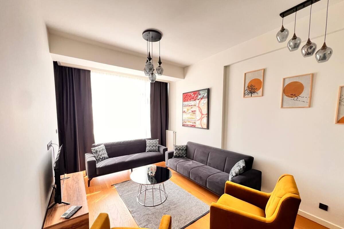 Un salon moderne avec un canapé, des fauteuils, une table basse et des œuvres d’art accrochées aux murs.
