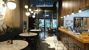 A modern restaurant interior with round tables, black chairs, and a bar area with stools. - G Tower Residence Apartment Rentals (Istanbul)