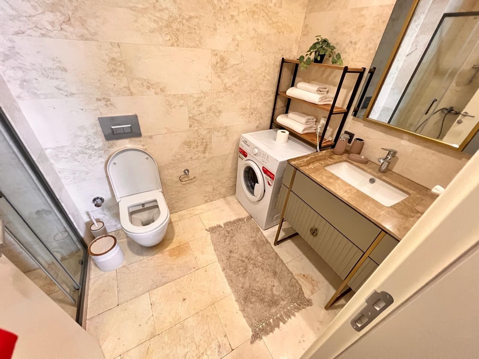 A modern bathroom with a toilet, washing machine, and sink.