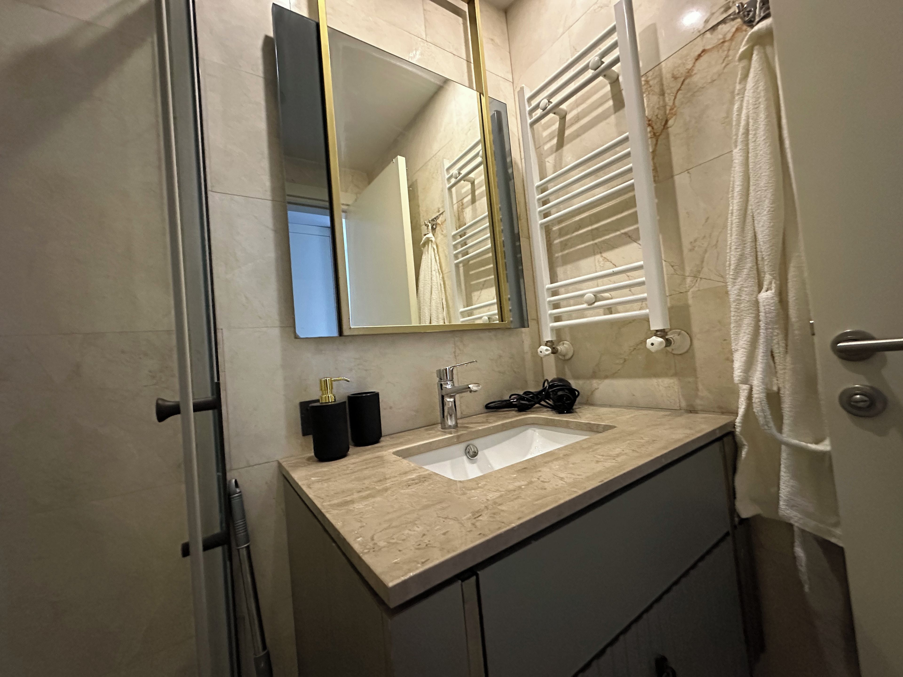 A bathroom with a sink, mirror, towel rack, and shower curtain.