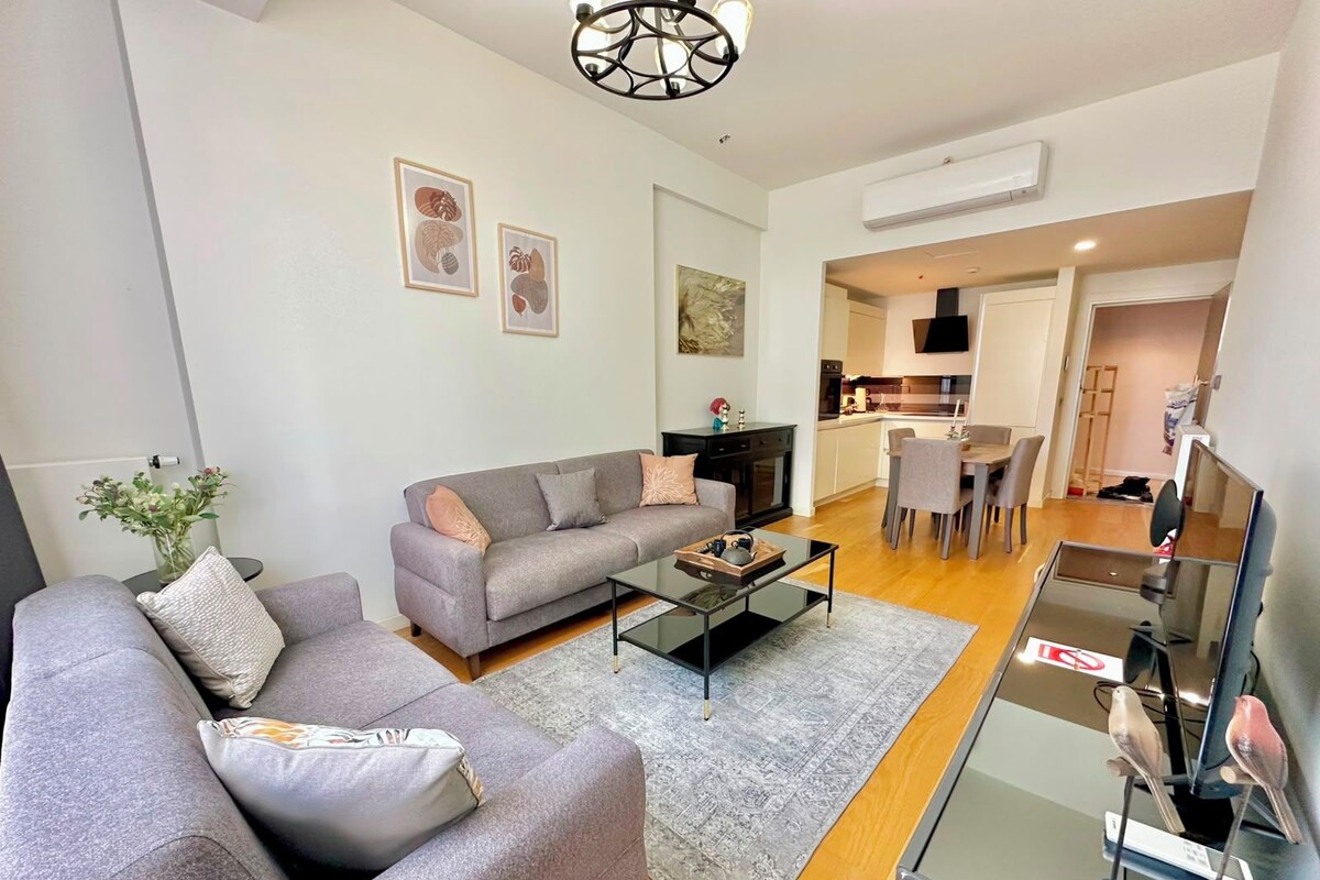 Una sala de estar moderna con un sofá gris, una mesa de centro y un televisor de pantalla plana.