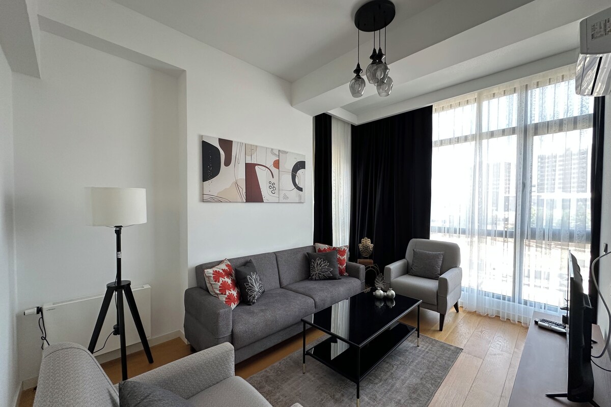 Una sala de estar moderna con un sofá, un sillón, una mesa de centro y un cuadro en la pared.