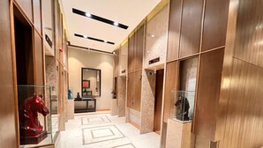 A modern hotel lobby with a marble floor, wooden paneling, and a glass display case with a horse statue. - G Tower Residence Apartment Rentals (Istanbul)
