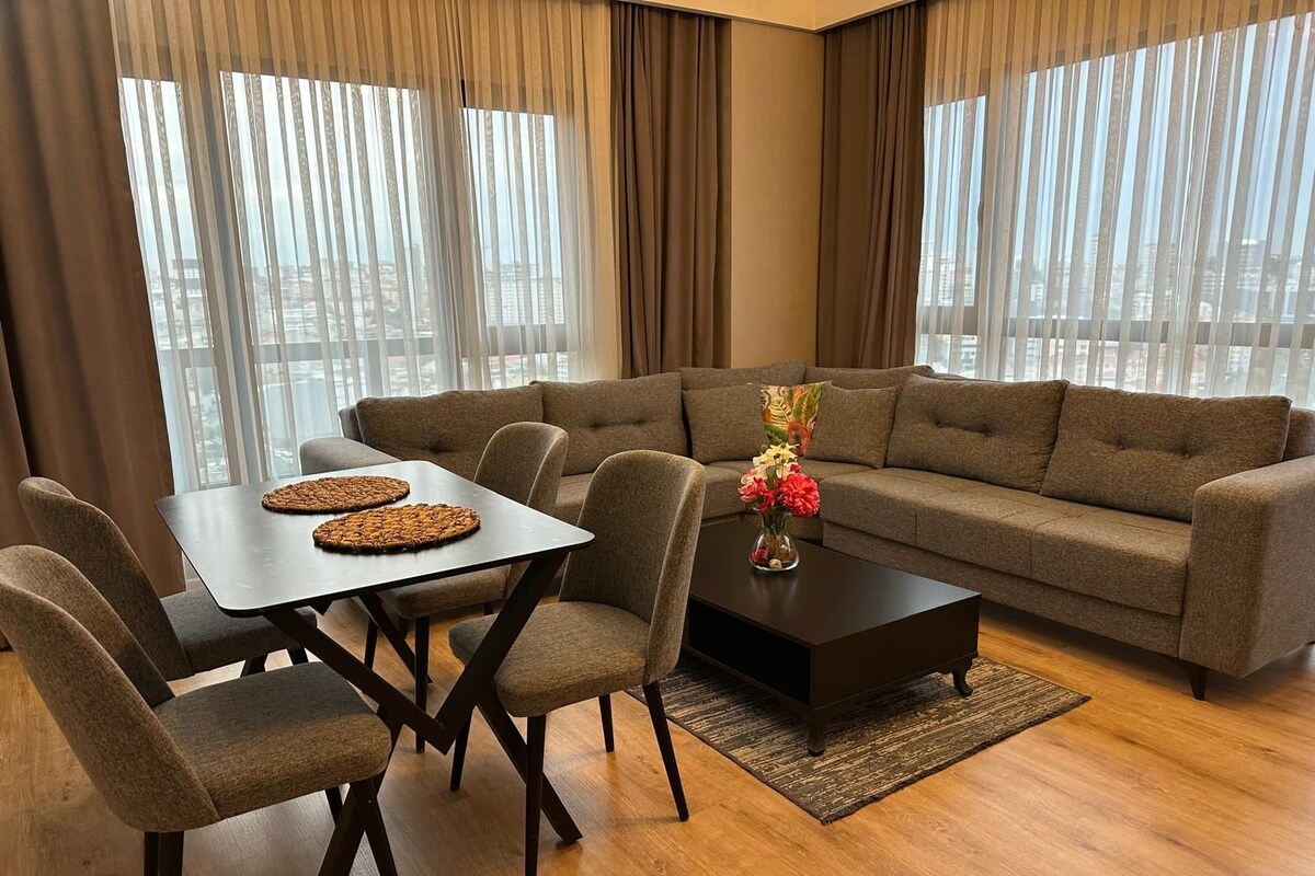 Una sala moderna con un sofá, una mesa de comedor con sillas y una mesa de centro con un jarrón de flores.