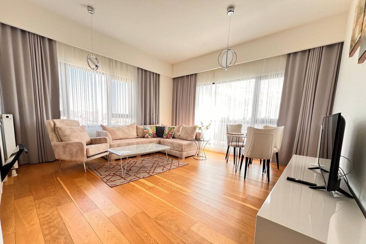 Un salon moderne avec un canapé d’angle, une table basse et un coin repas avec des chaises.