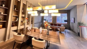 A modern dining area with a long table, multiple chairs, and a decorative ceiling light fixture. - G Tower Residence Apartment Rentals (Istanbul)