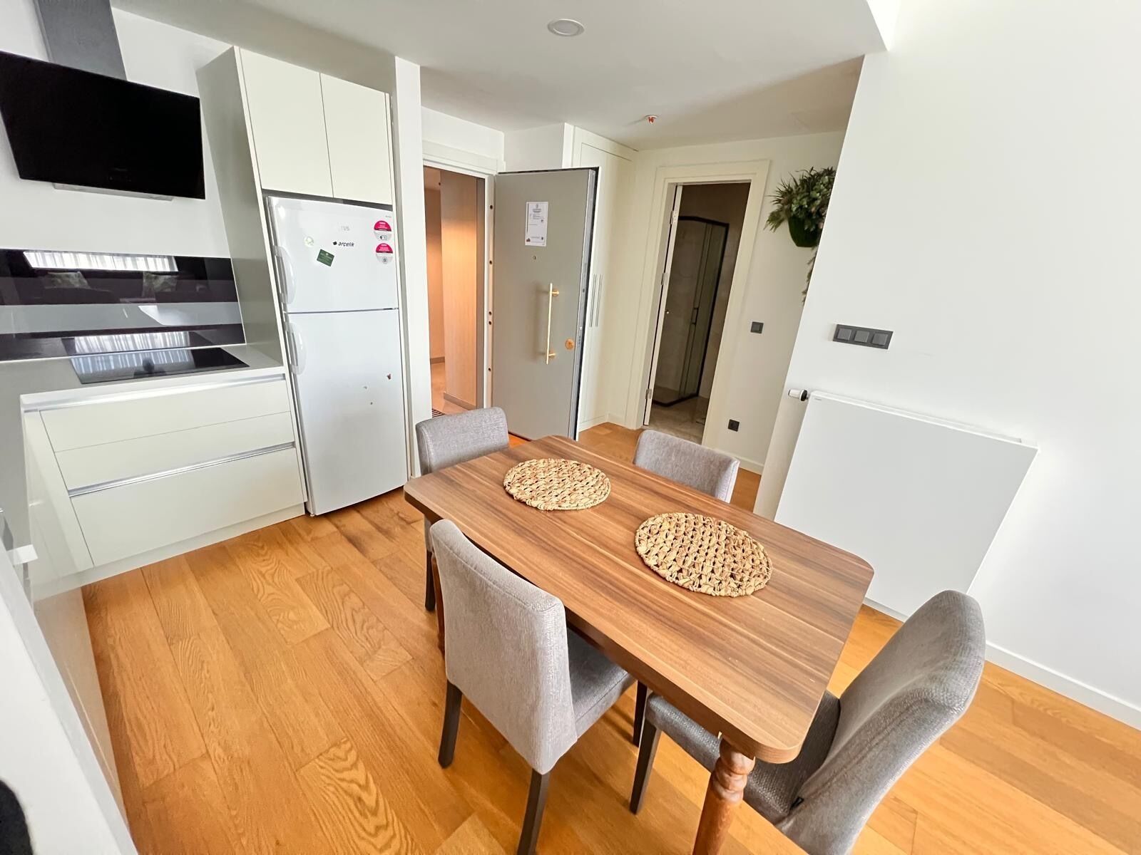 A compact kitchen with white cabinets, a built-in oven, and a dining table with four chairs.