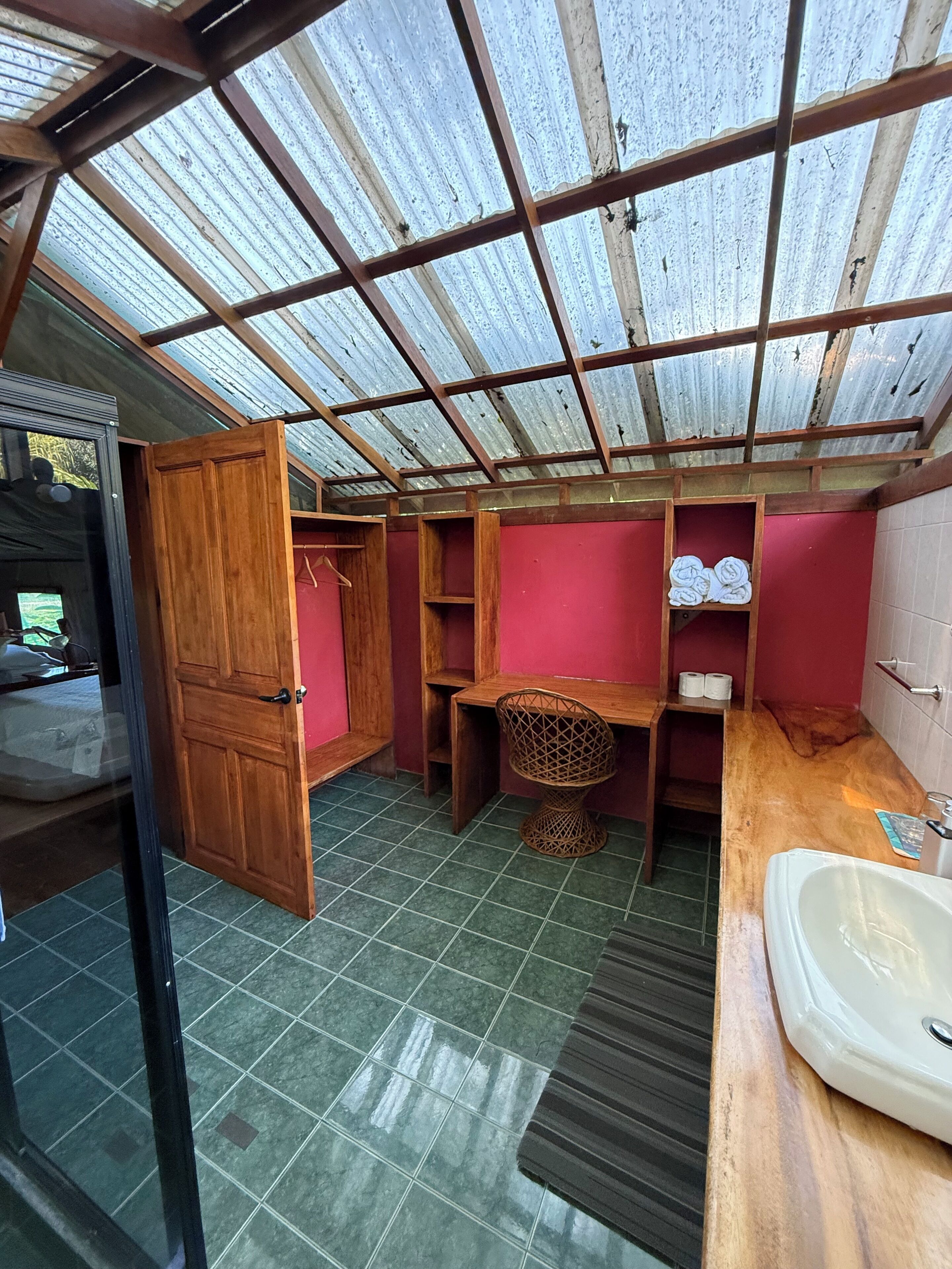 A compact bathroom with a skylight, a wooden door, a sink, and a shower area.