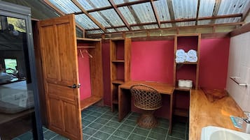 A compact bathroom with a skylight, a wooden door, a sink, and a shower area.