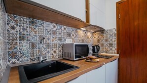 A kitchen with a black sink, a microwave, and a coffee maker on the countertop. - New! Studio partment A1 in Okrug Donji (Okrug Donji)
