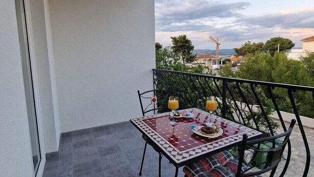 A balcony with a table set for two, featuring a checkered tablecloth and two glasses of orange juice. - New! Studio partment A1 in Okrug Donji (Okrug Donji)