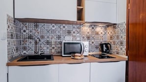 A compact kitchen with white cabinets, a microwave, a kettle, and a sink. - New! Studio partment A1 in Okrug Donji (Okrug Donji)