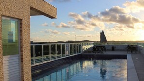 En pool på taget med glasgelænder, udsigt over landskabet og en klar himmel.