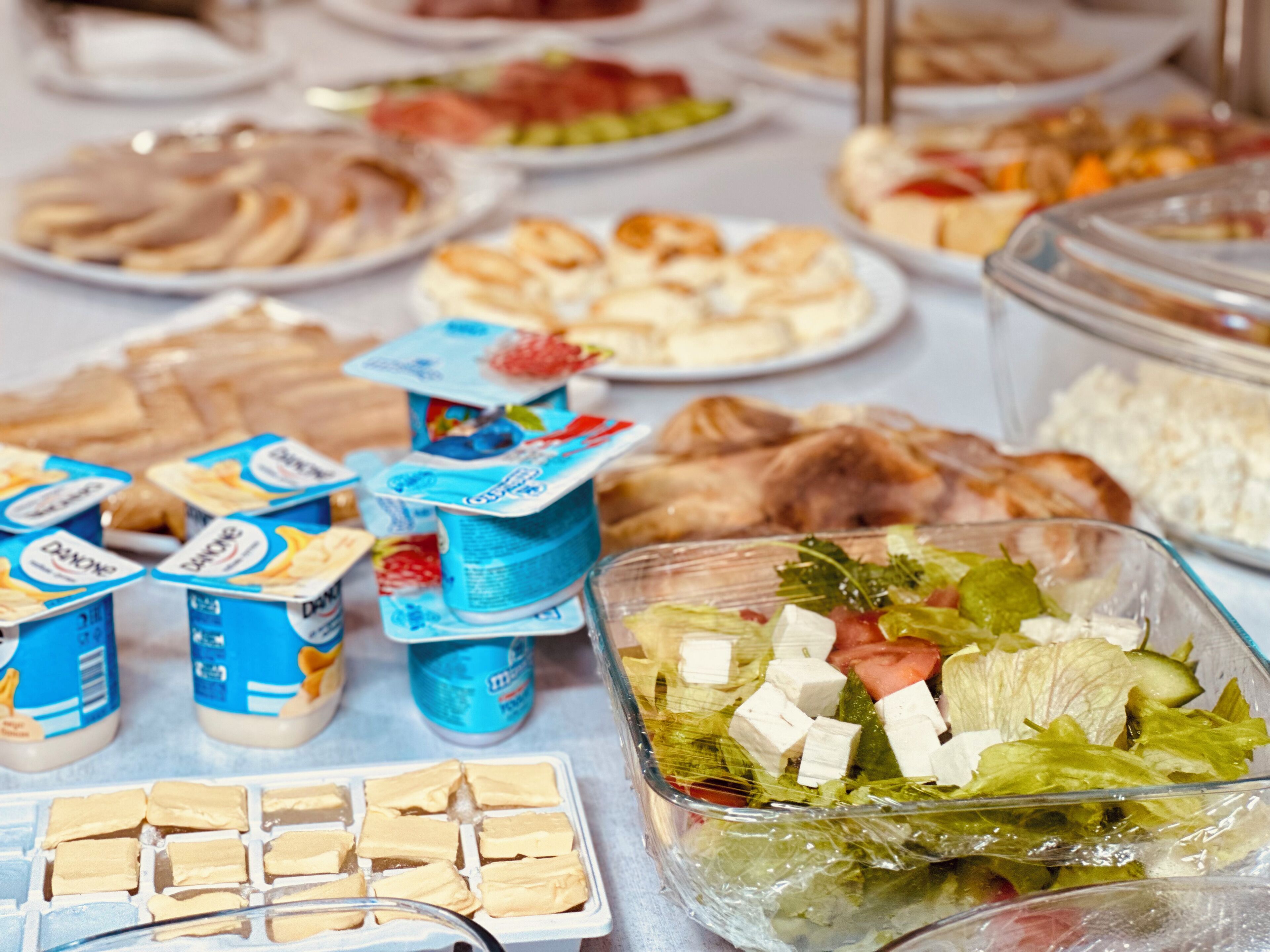 A buffet table with various food items including salads, cheeses, and yogurt.
