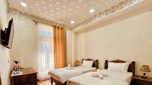 Habitación de hotel con dos camas, un escritorio, una silla y un televisor montado en la pared.