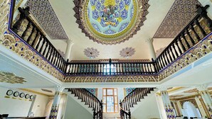 Una imponente escalera con detalles intrincados, un mostrador de recepción y vistas al área del vestíbulo.