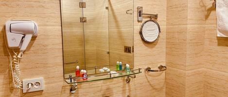 Baño con secador de pelo, espejo, lavabo y artículos de aseo.