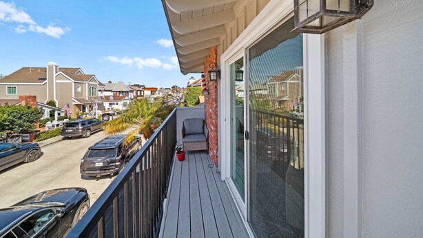 A balcony with a view of a residential street, a chair, and a lantern. - Ruby Villa B - Upper Unit for 6! (Newport Beach)